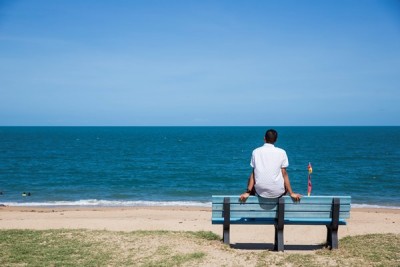 Person looking out at sea from atop a bench